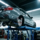 BMW sedan on hydraulic lift in garage showing chrome aftermarket coilover suspension system with LED lighting highlights