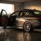 BMW sedan with lowered stance on coilovers in garage, driver door open showing leather interior, dramatic lighting on concrete floor