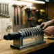 Mechanic adjusting chrome spring coil and black shock absorber on workbench with automotive tools in workshop lighting