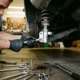 Mechanic's hands using wrench to install silver coilover suspension component on lifted car in garage workshop