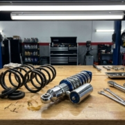 Coilover suspension system and lowering springs on automotive workbench with tools in professional garage setting