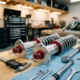 High-performance coilovers with chrome springs and red adjustment knobs on garage workbench with precision tools nearby