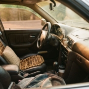 Cozy car interior with leather seats, wooden bead cushion, lumbar pillow, and essential oil diffuser in warm sunlight