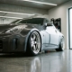 Lowered sports car with chrome wheels in modern garage, dramatic stance just inches from polished concrete floor.