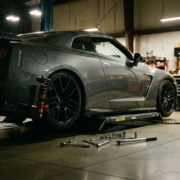 Lowered sports car on hydraulic lift in modern garage showing aftermarket suspension and coilovers with tools on floor