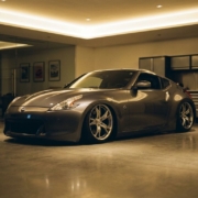 Lowered sports car with aggressive stance parked in modern garage with polished concrete floors and warm lighting.