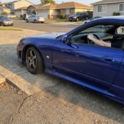 Lowered sports car with minimal ground clearance carefully navigating steep driveway entrance, front bumper nearly scraping pavement