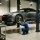 Mechanic inspecting lowered sports car suspension on automotive lift in professional garage with chrome wheels visible