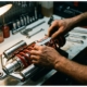 Mechanic adjusting chrome shock absorber and coil spring with precision tools on workbench in garage lighting