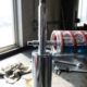 Chrome shock absorber with visible spring coils on automotive workbench under bright workshop lighting with tools