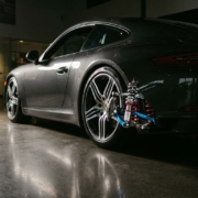 Sports car with lowered performance suspension system featuring exposed chrome coilovers in dramatic studio lighting