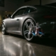 Sports car with lowered performance suspension system featuring exposed chrome coilovers in dramatic studio lighting