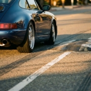 Lowered sports car navigating over speed bump with minimal clearance, chrome exhaust visible, golden hour lighting on asphalt road.
