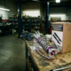 Custom-fabricated coilover suspension assembly with polished aluminum components on workbench next to boxed mass-produced kit