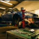 Mechanic adjusting red coilover suspension on lifted sports car in professional garage with specialized tools