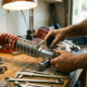 Mechanic's hands assembling custom car suspension system with chrome shock absorbers and coil springs on garage workbench