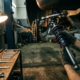 Mechanic inspecting chrome shock absorber and coil spring assembly under sports car with tools on workbench