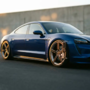 Modern electric car with lowered custom suspension and performance springs on asphalt during golden hour lighting