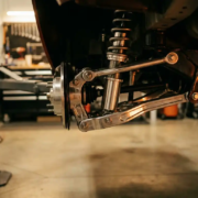 Porsche Cayman rear suspension with adjustable coilover dampers and polished aluminum components in professional garage