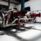 Porsche GT3 rear suspension assembly with precision coilover dampers and anti-roll bars in white garage with dramatic lighting