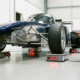 Race car positioned on four digital corner weight scales in professional garage with bright lighting and concrete floors
