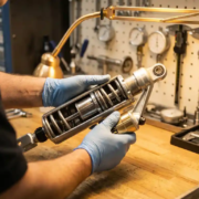 Technician's hands examining cutaway shock absorber showing internal components on workbench with specialized tools and gauges