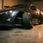 Sports car with extreme negative camber wheel angle and stressed suspension geometry on concrete garage floor