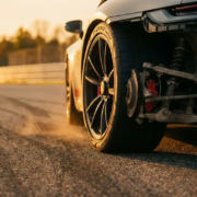 Sports car rear wheel and suspension assembly during high-speed cornering on race track with golden hour lighting