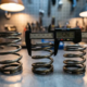 Three coiled suspension springs with varying wire thicknesses on metal workbench, precision calipers measuring spring diameter