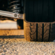 High-performance tire cross-section showing detailed contact patch on asphalt with precision suspension component in background under golden hour lighting