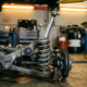 Car's rear shock absorber at full compression with chrome piston rod extended to maximum travel in professional garage