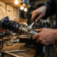 Mechanic's hands adjusting coilover suspension unit with precision tools on workshop bench, spring components and dials visible