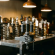 Custom shock absorber on a workshop bench surrounded by competitor suspension components, polished aluminum damper under warm directional lighting.