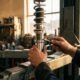 Mechanic's hands adjusting coilover suspension strut with specialized tool in professional garage workshop