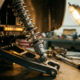 Chrome shock absorber fully extended on performance car's rear suspension assembly with precision-machined aluminum components