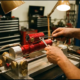Mechanic's hands adjusting red anodized shock absorber with precision tools in professional suspension tuning rig