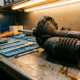 Worn car shock absorber with oil leakage and damaged rubber boot on automotive workshop bench with precision tools nearby